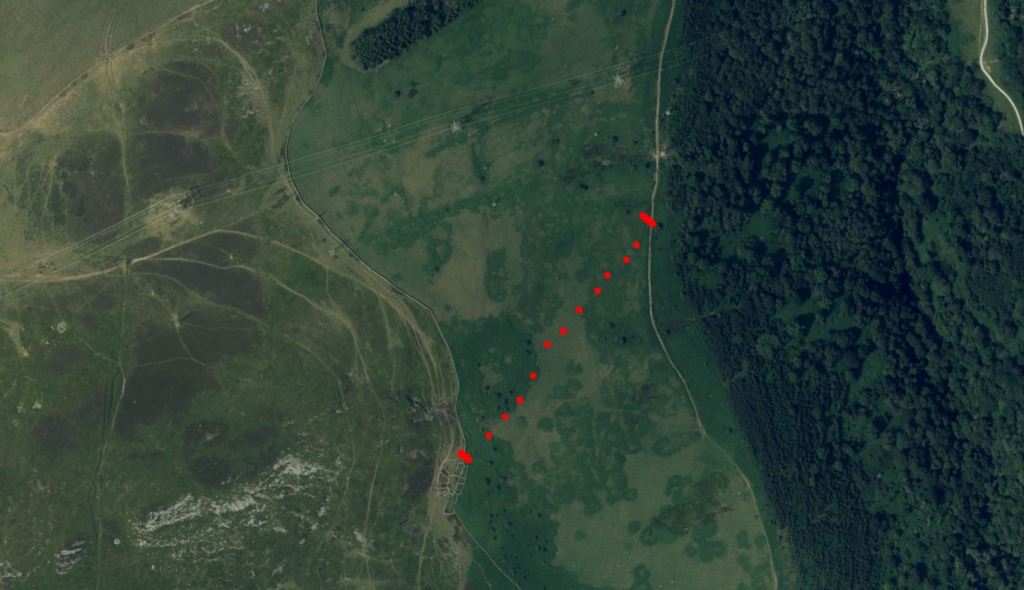 Aerial map showing a footpath highlighted with red markers, with green fields and wooded areas in the background.