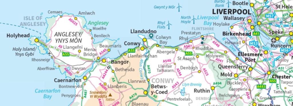 A detailed map of the Anglesey region in Wales, showing locations such as Holyhead, Caernarfon, Llandudno, and Conwy, along with major roads and geographical features.